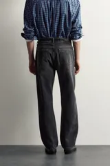 Jeans straight fit de corte recto y tiro medio, confeccionados en denim de algodón rígido con efecto lavado en color negro, de la colección especial Aaron Levine x Zara. Presentan diseño clásico de cinco bolsillos y cierre frontal con botonadura.