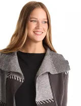 Cardigan largo tejido con diseño patchwork en tonos grises y negros. Presenta cuello con amplia solapa, diseño abierto sin botones y bolsillos delanteros amplios.
