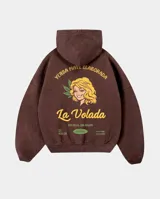 Canguro oversize color marrón con capucha y bolsillo frontal. Presenta un estampado gráfico en la espalda que incluye una ilustración de una mujer, texto decorativo y detalles alusivos a yerba mate.