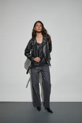 Campera estilo biker de cuero sintético negro, con solapas amplias, cierre frontal asimétrico, bolsillos laterales con cierre y cinturón ajustable en la cintura.