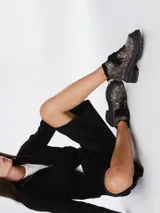 Borcego de punta redonda con efecto cuero desgastado, cordones y tira de velcro frontal. Cuenta con suela track y herrajes metálicos.