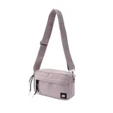 Bandolera de lona color lila, con cierre principal y bolsillo frontal. Incluye correa ajustable con logo grabado y tiradores con cordones decorativos.