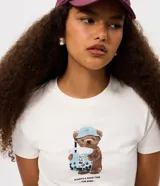 Remera blanca con cuello redondo y mangas cortas, confeccionada en algodón con elastano. Presenta una estampa frontal de un oso sosteniendo un vaso de boba con la frase "Always a good time for boba".