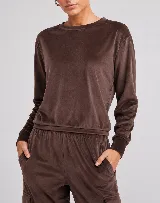 Buzo cropped de cuello redondo y manga larga, confeccionado en tejido plush ultrasuave con acabado aterciopelado. Presenta un corte relajado con puños y ruedo acanalados.