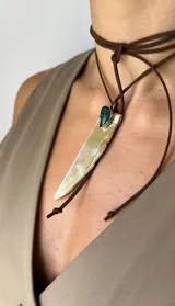 Gargantilla con tira de cuero marrón que se ata al cuello, dije de nácar con forma de colmillo y aplique de crisocola engarzado en alpaca.