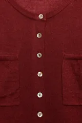 Chaqueta de punto bordó con cuello redondo, manga larga y bolsillos de plastrón en el delantero. Cuenta con cierre frontal de botones.