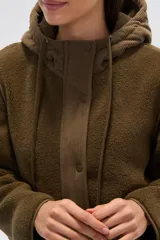 Campera de diseño híbrido en color verde oliva, que combina paneles de corderito en la parte superior y capucha con una sección inferior acolchada con diseño de rombos. Cuenta con cierre frontal, botones a presión y bolsillos frontales con solapa.