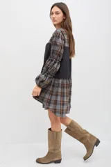 Vestido midi de corte holgado con diseño combinado en tela escocesa gris y naranja y panel central negro. Presenta cuello mao, cierre frontal con botones, mangas largas abullonadas con detalles de volados y puños elásticos.