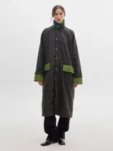 Trench oversize de lana a cuadros con cuello, puños y bolsillos de pana verde.