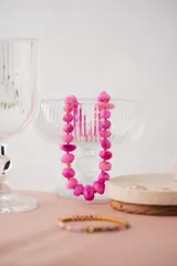 Collar corto de piedras irregulares color fucsia y detalles dorados.