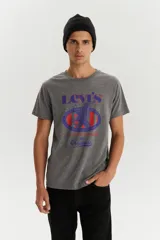 Remera de manga corta y cuello redondo color gris jaspeado. Presenta un estampado gráfico frontal con el logo de Levi's, un águila y detalles en tonos azul y rojo.