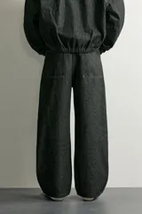 Jeans wide fit de denim negro, con costuras y detalles en color verde claro, bolsillos laterales y traseros, y cintura ajustable con cordón integrado.