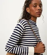 Sweater de punto de manga larga, con rayas horizontales en azul marino y blanco. Presenta cuello redondo ligeramente elevado y puños y ruedo en color blanco liso.