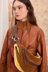 Riñonera cruzada de gamuza marrón, amarilla y borgoña con correa de cuero ajustable y cierre de cremallera.