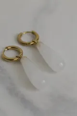 Aros tipo argolla con dije colgante en forma de gota de piedra natural en tonos marrones. Fabricados en acero quirúrgico dorado.