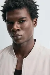 Cazadora bomber ligera de tejido técnico color verde oliva, con cuello, puños y bajo en rib elástico. Presenta cierre frontal de cremallera y bolsillos de vivo en la cadera.