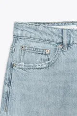 Bermuda jorts de denim celeste con efecto lavado, tiro bajo y cinco bolsillos. Cierre frontal con cremallera y botón metálico.