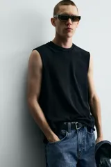 Camiseta tank de punto de algodón, color negro, de corte relaxed fit con cuello redondo, manga sisa y acabados irregulares.