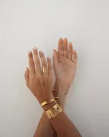 Pulsera tipo esclava abierta con diseño rústico y acabado irregular, fabricada en bronce y alpaca.