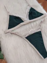 Conjunto de lencería compuesto por bralette triangular y tanga, confeccionado en algodón color verde inglés con detalles de encaje en tono nude. El bralette cuenta con breteles ajustables y broche regulable, mientras que la tanga presenta laterales ajustables.