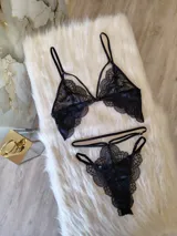 Conjunto de lencería de encaje negro compuesto por un bralette con detalle de aro central y una tanga de doble tira regulable estilo less.