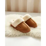 Pantuflas de gamuza color beige con plataforma y forro interior de corderito sintético. Presentan un diseño sin talón con el nombre de la marca bordado en el lateral.