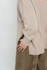 Sweater color crudo de punto, con cuello redondo y corte suelto.
