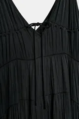 Vestido midi negro satinado con escote en pico, tirantes finos y detalle de lazada frontal. Presenta diseño de paneles fruncidos.