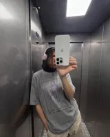 Remera de corte oversize color gris con efecto stone wash. Presenta un estampado gráfico central enmarcado en un recuadro negro, que muestra una silueta humana rodeada por líneas curvas de color violeta y el texto 'FIG. 1 LOS DE AFUERA SON DE PALO'.