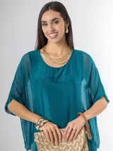 Vestido midi de seda italiana color negro, diseño dos en uno con capa superior de calce amplio, falda con volados y forro interior de algodón elastizado.
