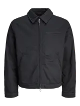 Campera estilo worker de color negro, con cuello camisero, cierre frontal con cremallera y bolsillos laterales. Presenta un diseño minimalista y funcional con acabado limpio.