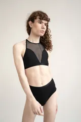 Top negro confeccionado en lycra y tela de malla semitransparente, con diseño de cuello halter y ajuste posterior.
