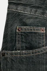 Jeans de tiro medio y corte baggy oversize con diseño de costuras marcadas en las piernas, trabillas para cinturón y cinco bolsillos tradicionales. Cierre frontal con cremallera y botón metálico.