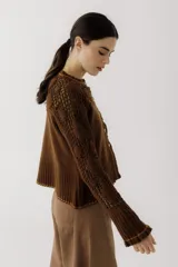 Saco de punto color beige, con diseño de calados en la parte superior y mangas, cierre frontal con botones y cuello redondo.