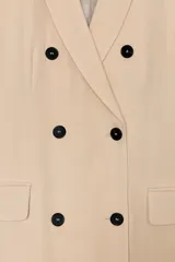 Abrigo largo de corte recto y diseño fluido, confeccionado en tejido con mezcla de lino. Presenta cuello con solapas, cierre frontal cruzado con botones en contraste y bolsillos laterales con solapa.