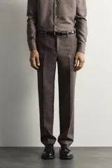 Pantalón de traje regular fit marrón con sutil estampado a cuadros, confeccionado en mezcla de lino y lana. Cuenta con bolsillos delanteros, bolsillos traseros de doble vivo con botón y raya marcada en el centro de las piernas.