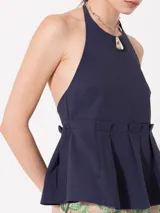 Top azul marino de poplín elastizado, con cuello halter que se ata con lazo. Tiene espalda descubierta y faldón con tablas superpuestas.