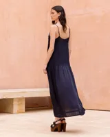 Vestido largo negro con tirantes finos ajustables, cuerpo con plisado fino y detalle de hilera de botones decorativos en el lateral. Cuenta con una falda amplia y fluida con abertura lateral.