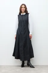 Maxi vestido sin mangas de denim oscuro, con corte al cuerpo en el torso y falda acampanada que cae hasta el tobillo. Presenta costuras visibles en contraste que definen los paneles del vestido.