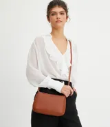 Bolso baguette pequeño color negro, con correa transversal ajustable y bolsillo interno con cremallera. Textura tipo saffiano y cierre por cremallera.