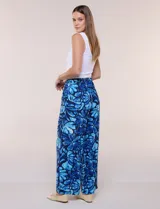 Pantalón de poliéster de corte ancho tipo palazzo y calce relajado, con estampado de hojas en tonos azules, cintura alta elastizada con cordón ajustable y bolsillos laterales.