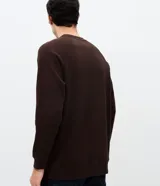 Buzo masculino de textura waffle, con cuello redondo y mangas largas. Confeccionado en una mezcla de algodón y poliéster, presenta un diseño cerrado y minimalista.