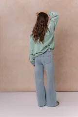 Pantalón de jean color arena con silueta wide leg, tiro medio-alto y costuras verticales delanteras que estilizan la figura. Cuenta con bolsillos funcionales y cierre frontal con doble botón.