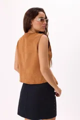 Chaleco color crema con escote en V y cierre frontal con lazos. Presenta detalles de puntilla en el escote y calados en los laterales.