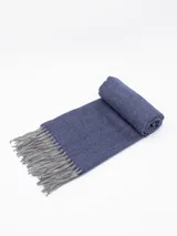 Bufanda de tejido de punto con diseño de espiga en color azul, con flecos en los extremos en color gris.