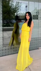 Vestido largo amarillo de estilo strapless, con cuerpo drapeado y falda fluida con tajo lateral.