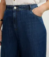 Pantalón de jean modelo wide leg, de tiro medio y corte amplio desde la cadera hasta el ruedo. Presenta cierre frontal con botón, bolsillos laterales y traseros, y trabillas en la cintura.
