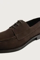 Zapato estilo náutico de hombre, confeccionado en piel con acabado serraje en color marrón, con cordones finos y detalle de bordón en el empeine.
