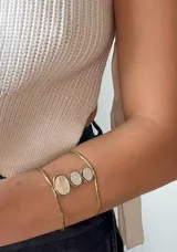 Brazalete de brazo dorado con tres dijes circulares de nácar.