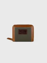 Billetera de cuero con cierre perimetral, combinando cuero liso color tostado en los bordes y cuero texturizado color verde oliva en el centro. Incluye un parche de cuero oscuro con logo grabado en la parte frontal.